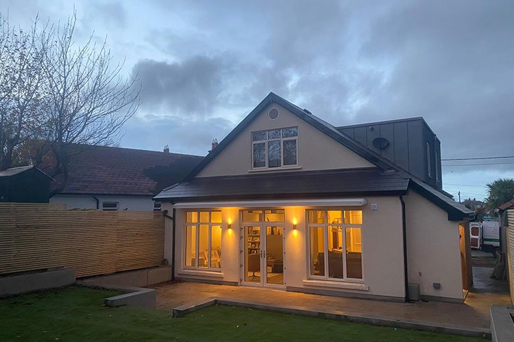 A house at dusk with warm light in the windows of a newly built rear extension
